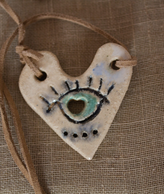 Colgante de cerámica artesanal en forma de corazón con un ojo pintado