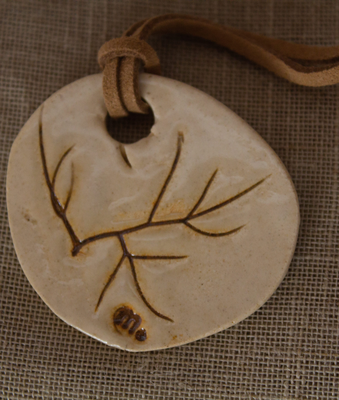 Colgante redondo de cerámica artesanal con relieve de hoja