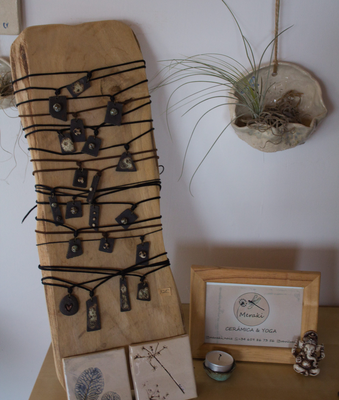 Expositor de madera con colgantes de cerámica artesanal en el taller