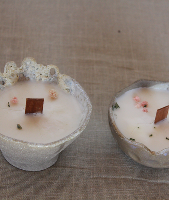 Portavelas de cerámica artesanal con velas de cera y pétalos secos