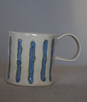 Taza de cerámica artesanal blanca con rayas azules y asa redonda