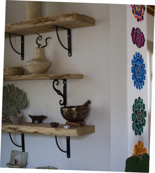 Estanterías de madera del taller de Meraki con piezas de cerámica y un cuenco tibetano